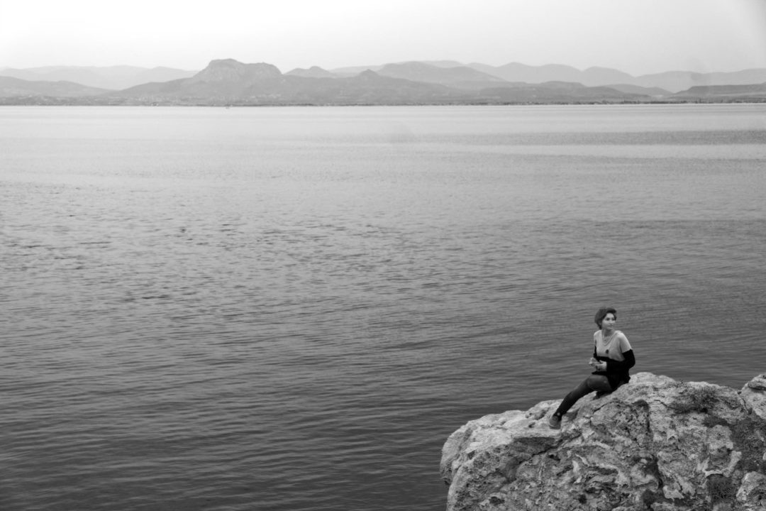 The way this woman is sitting on the rocks makes her appear like a siren. The mountains on the background are hardly visible through the haze
